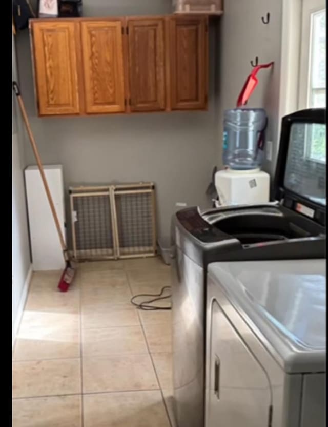 clothes washing area with light tile patterned flooring, cabinets, and washer and dryer