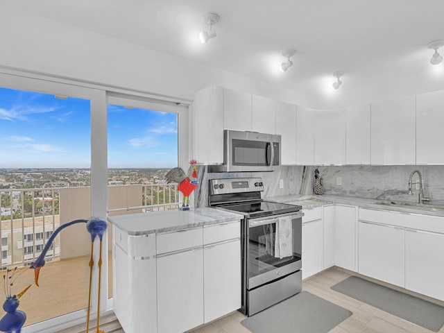 3000 S Ocean Blvd Unit 1504, Boca Raton, FL 33432 - kitchen featuring stainless steel appliances, a sink, white cabinets, tasteful backsplash, and light stone counters