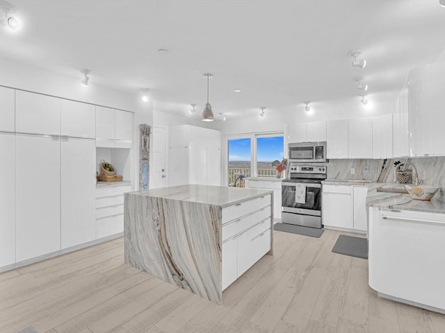 kitchen featuring appliances with stainless steel finishes, white cabinetry, a center island, decorative backsplash, and decorative light fixtures