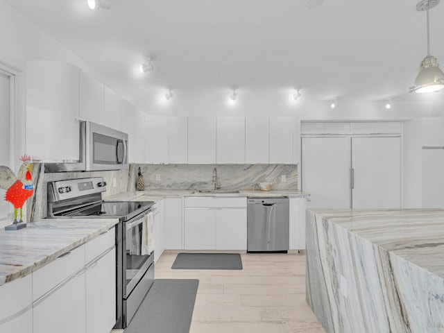 kitchen featuring appliances with stainless steel finishes, white cabinetry, sink, backsplash, and hanging light fixtures