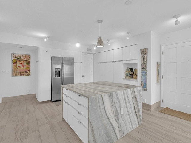 kitchen featuring white cabinetry, pendant lighting, a kitchen island, and stainless steel refrigerator with ice dispenser