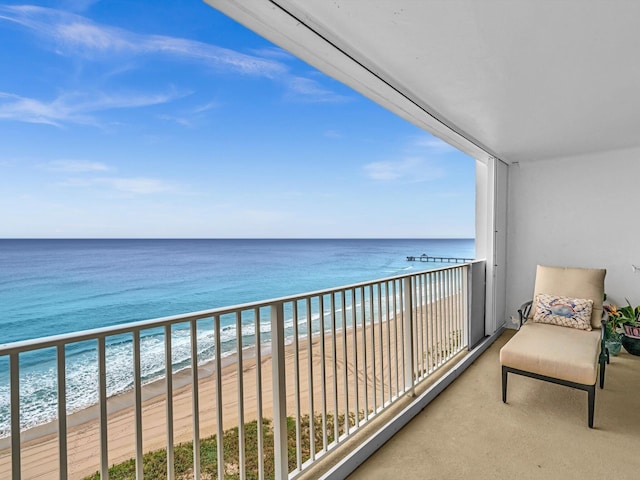 balcony with a water view and a view of the beach