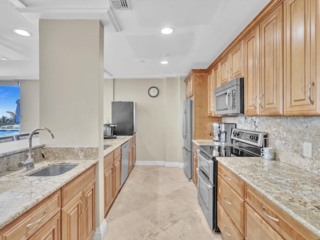 kitchen featuring light stone countertops, appliances with stainless steel finishes, sink, and backsplash