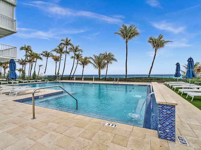 view of pool with a water view, pool water feature, and a patio