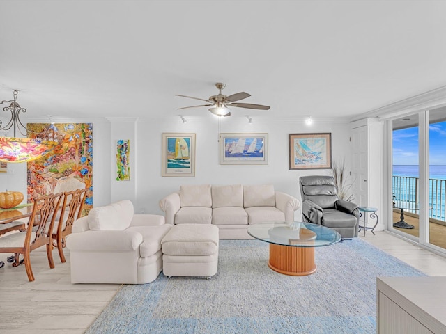 living room with crown molding, floor to ceiling windows, ceiling fan, and a water view