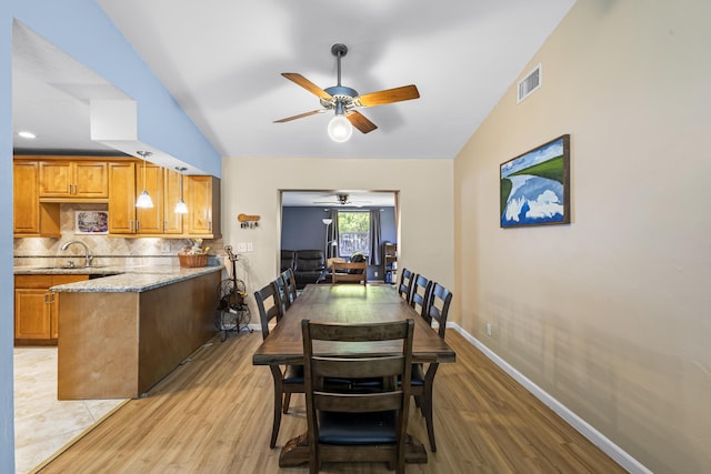 dining room with ceiling fan, lofted ceiling, sink, and light wood-type flooring