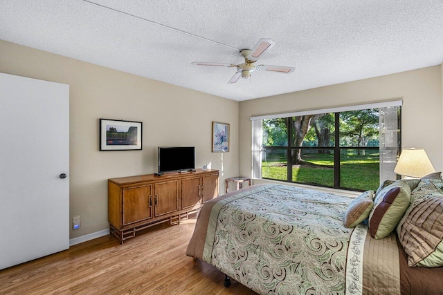 bedroom featuring ceiling fan, light hardwood / wood-style floors, and a textured ceiling