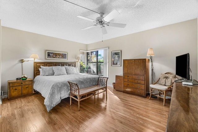 bedroom with ceiling fan, a textured ceiling, and light wood-type flooring