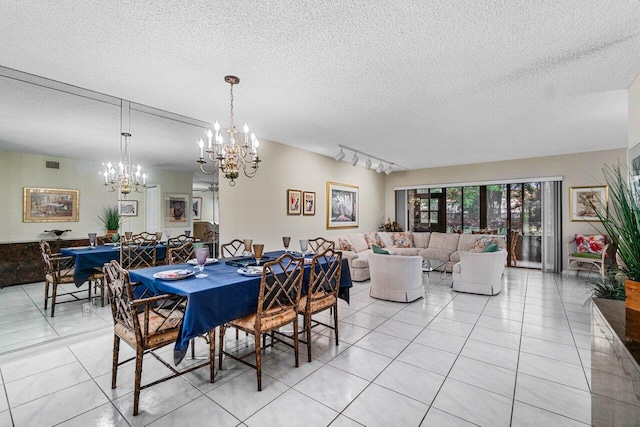 dining room with light tile patterned floors, rail lighting, and a textured ceiling