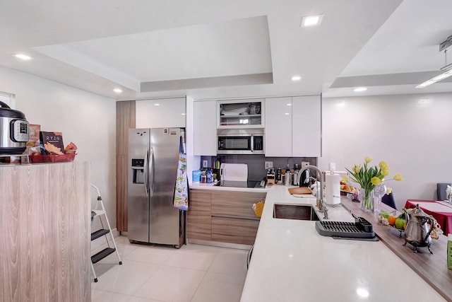 kitchen with sink, light tile patterned floors, white cabinetry, stainless steel appliances, and a tray ceiling