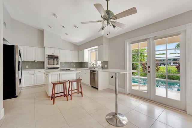 kitchen featuring vaulted ceiling, backsplash, a kitchen island, a breakfast bar area, and stainless steel appliances