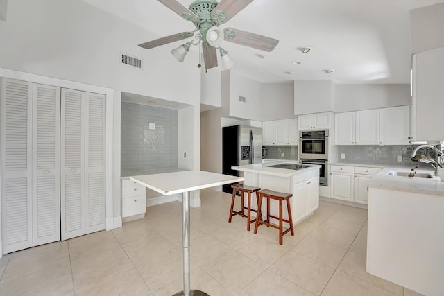 kitchen featuring tasteful backsplash, white cabinetry, sink, a kitchen island, and high vaulted ceiling