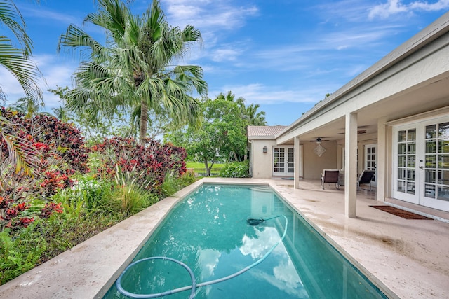 view of swimming pool featuring ceiling fan, french doors, and a patio area