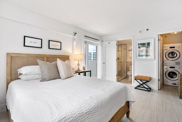 bedroom with stacked washer and dryer, light wood-type flooring, and ensuite bathroom