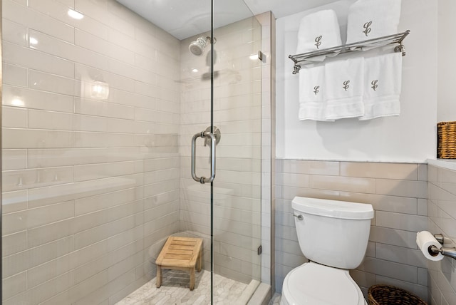 bathroom with tile walls, an enclosed shower, and toilet