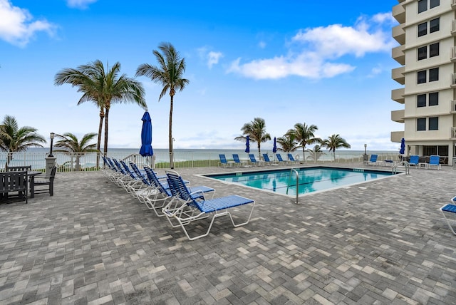 view of swimming pool featuring a patio area and a water view