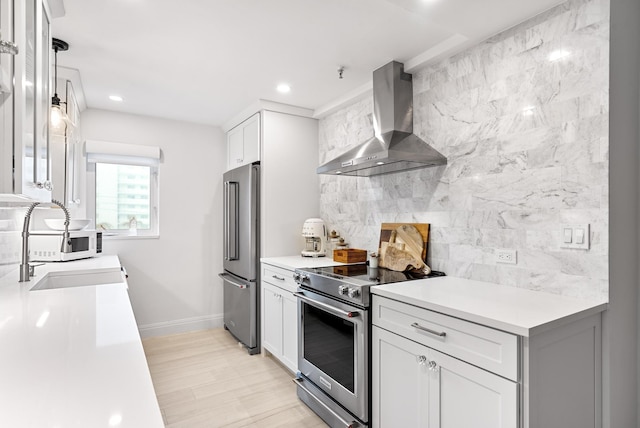 kitchen featuring wall chimney exhaust hood, white cabinetry, tasteful backsplash, light wood-type flooring, and stainless steel appliances