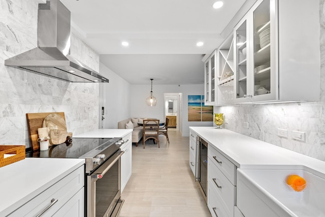 kitchen with pendant lighting, stainless steel range with electric stovetop, white cabinetry, extractor fan, and beverage cooler