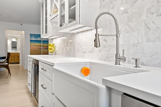 kitchen featuring sink, white cabinets, and beverage cooler