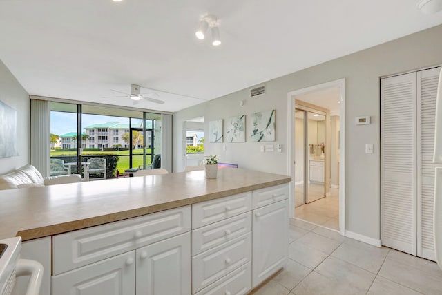 kitchen with light tile patterned floors, visible vents, white cabinets, open floor plan, and light countertops