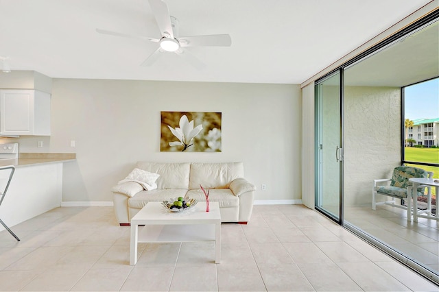 living room with expansive windows, light tile patterned flooring, a ceiling fan, and baseboards