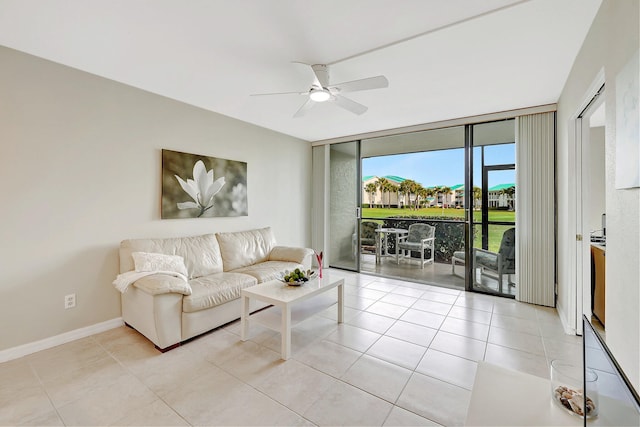 living area with light tile patterned floors, ceiling fan, expansive windows, and baseboards