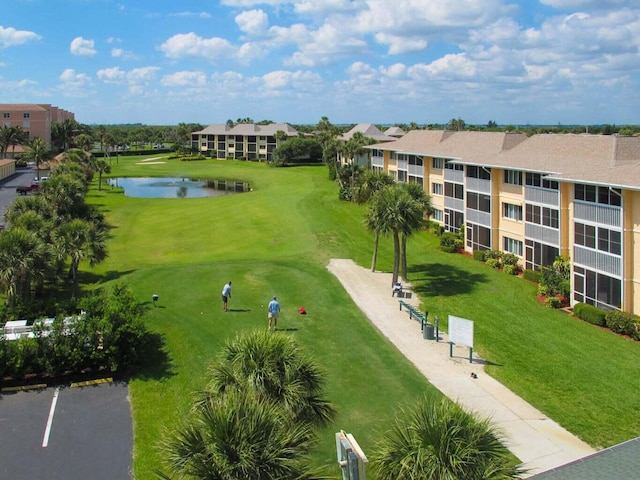 surrounding community with a water view and a lawn