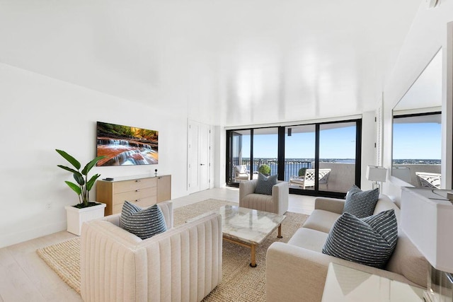 living room featuring a wall of windows and light hardwood / wood-style floors