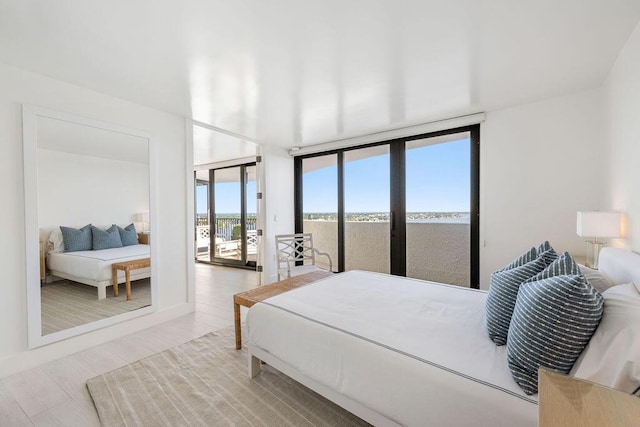 bedroom featuring access to exterior, expansive windows, and light hardwood / wood-style flooring