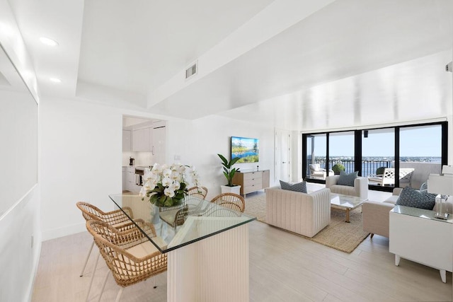 living room with a wall of windows and light hardwood / wood-style flooring