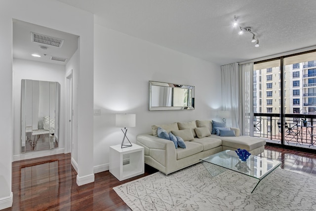 living room with a wall of windows, wood-type flooring, and a textured ceiling