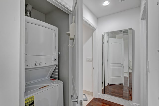 clothes washing area with stacked washing maching and dryer and dark wood-type flooring