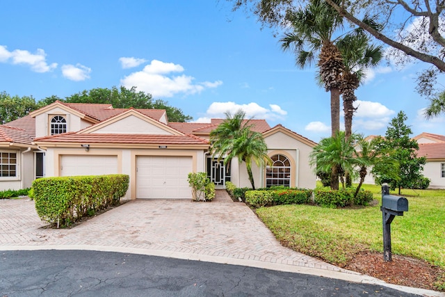 mediterranean / spanish-style house featuring a garage and a front lawn