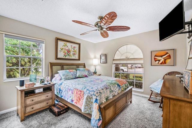 bedroom featuring light colored carpet, a textured ceiling, and ceiling fan