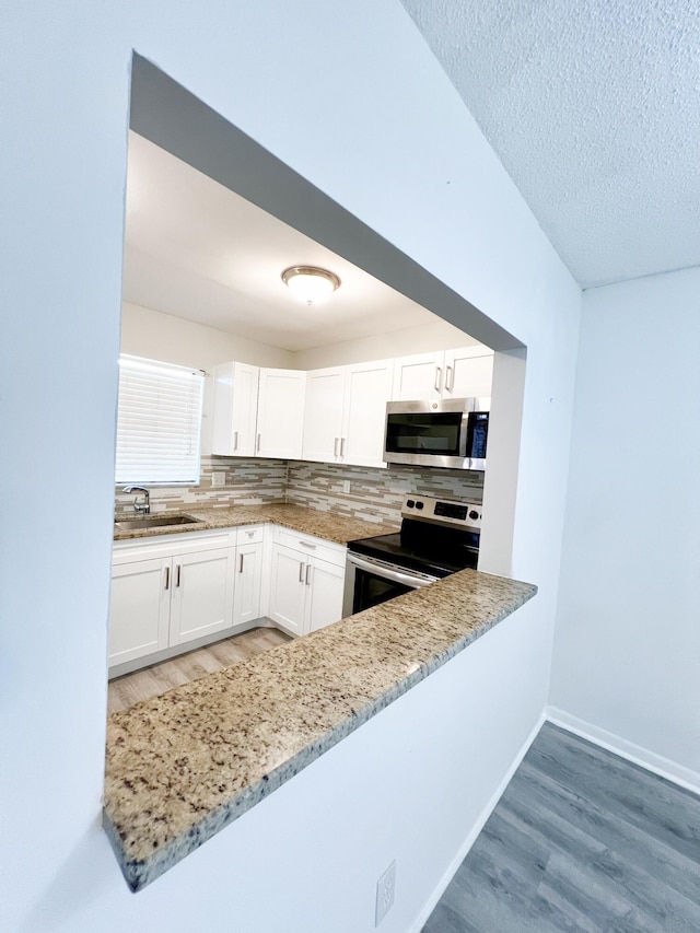 kitchen featuring light stone countertops, white cabinets, appliances with stainless steel finishes, decorative backsplash, and sink