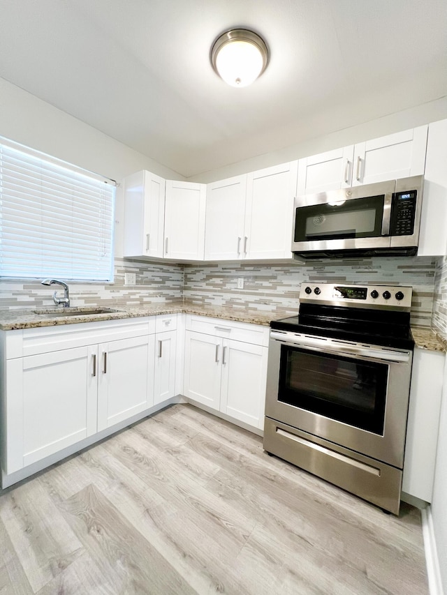 kitchen featuring sink, white cabinets, light stone countertops, and stainless steel appliances