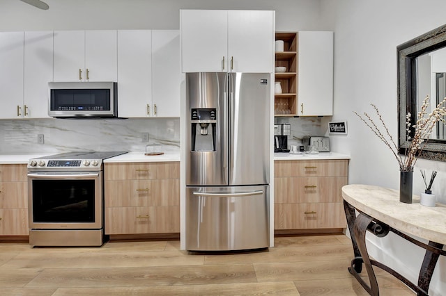 kitchen featuring white cabinetry, appliances with stainless steel finishes, light wood-type flooring, and decorative backsplash