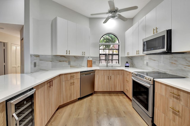 kitchen featuring white cabinetry, tasteful backsplash, beverage cooler, and appliances with stainless steel finishes