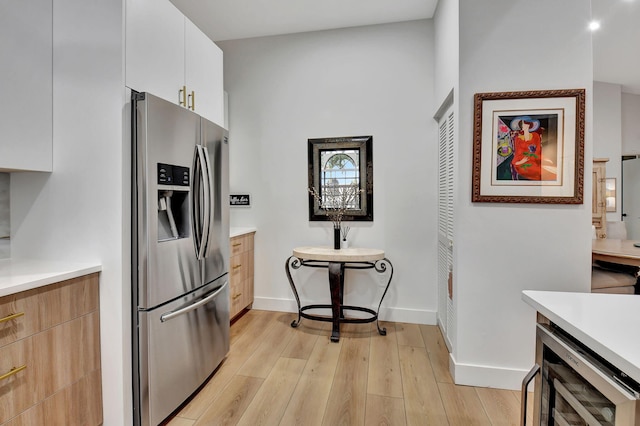 kitchen featuring stainless steel refrigerator with ice dispenser, white cabinets, and light hardwood / wood-style floors