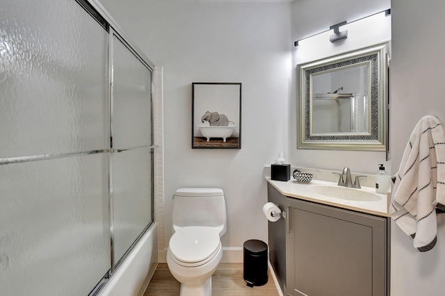 full bathroom featuring hardwood / wood-style flooring, vanity, combined bath / shower with glass door, and toilet