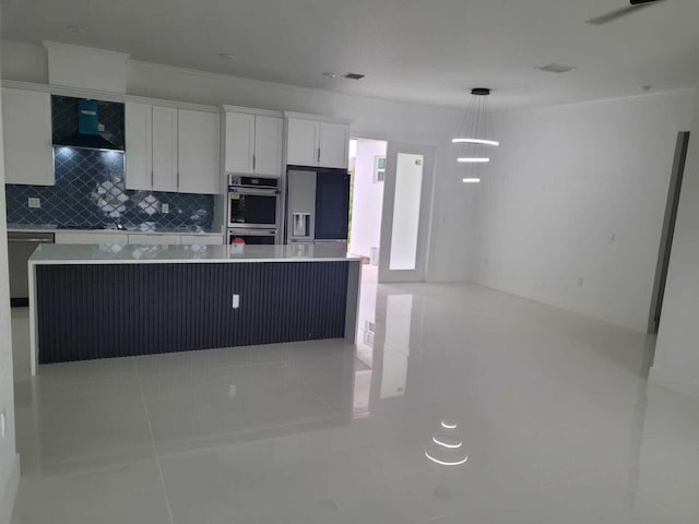 kitchen featuring appliances with stainless steel finishes, white cabinets, decorative backsplash, decorative light fixtures, and wall chimney exhaust hood