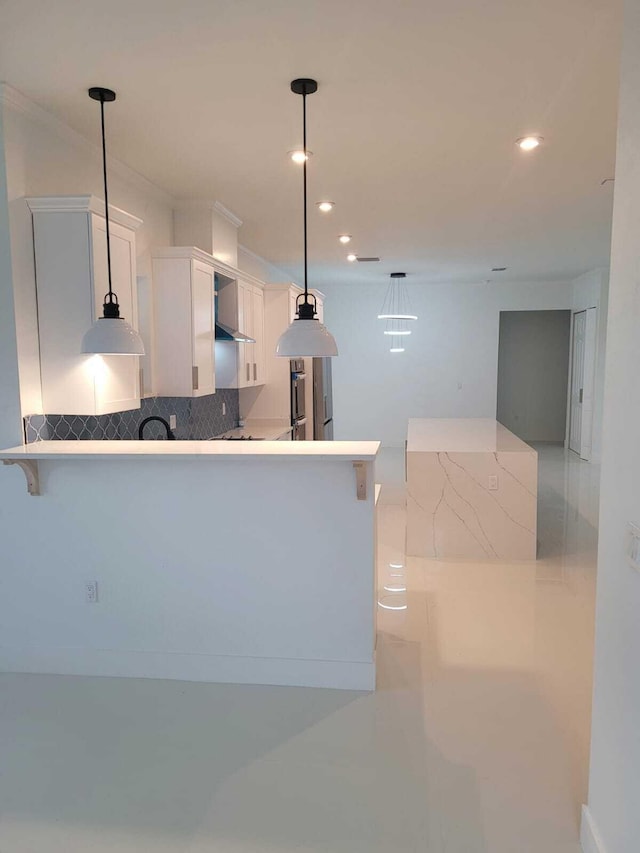 kitchen featuring a kitchen bar, white cabinetry, tasteful backsplash, hanging light fixtures, and kitchen peninsula