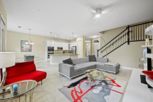 tiled living room with ceiling fan with notable chandelier