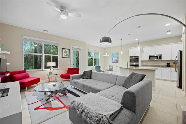 living room with ceiling fan, sink, and light tile patterned floors