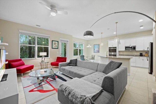 living room featuring ceiling fan, sink, and light tile patterned floors