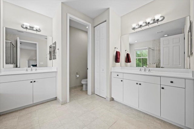 bathroom featuring toilet, a shower with shower door, and vanity