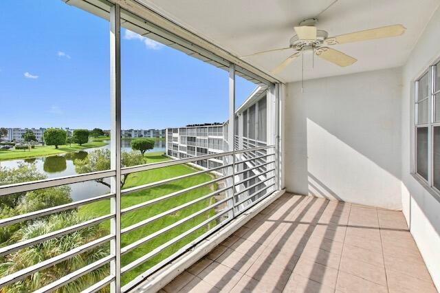 unfurnished sunroom with ceiling fan and a water view