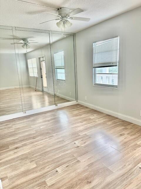 unfurnished bedroom with ceiling fan, light hardwood / wood-style flooring, and a textured ceiling