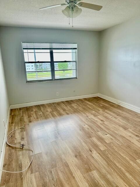 spare room with ceiling fan, a textured ceiling, and light wood-type flooring