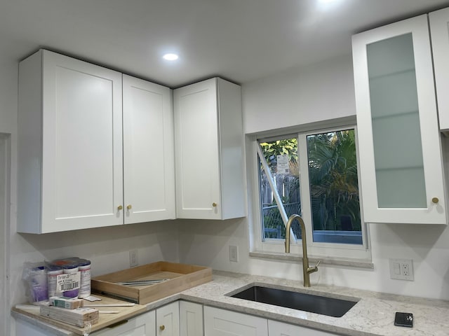 kitchen with sink, white cabinetry, and light stone countertops